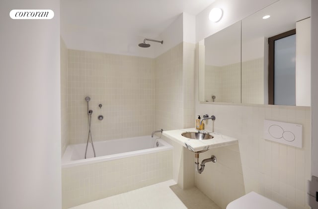 full bath featuring a relaxing tiled tub, a sink, toilet, tile walls, and a shower