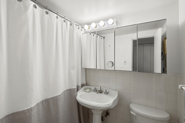 full bath featuring toilet, a sink, tile walls, and a shower with curtain