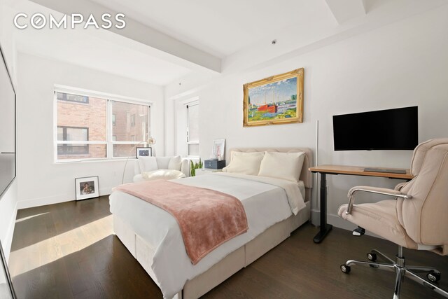 bedroom with dark wood finished floors, beam ceiling, and baseboards