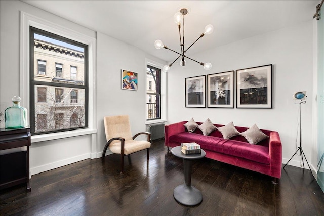 living room featuring a wealth of natural light, a notable chandelier, radiator, and wood finished floors