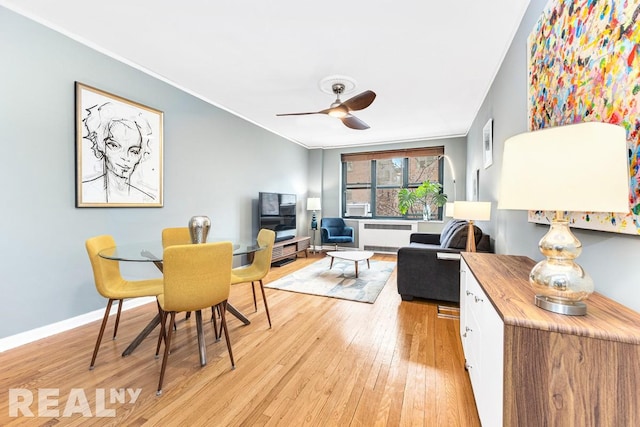 living area with radiator, light wood-style flooring, ornamental molding, ceiling fan, and baseboards