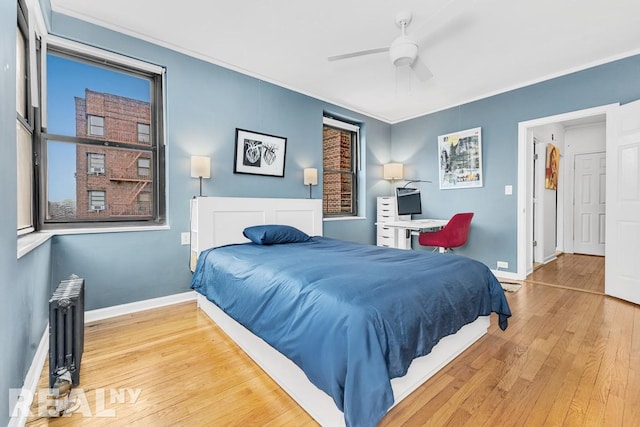 bedroom featuring radiator heating unit, ornamental molding, a ceiling fan, wood finished floors, and baseboards