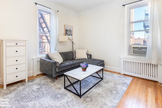 living room featuring cooling unit, plenty of natural light, radiator heating unit, and hardwood / wood-style flooring