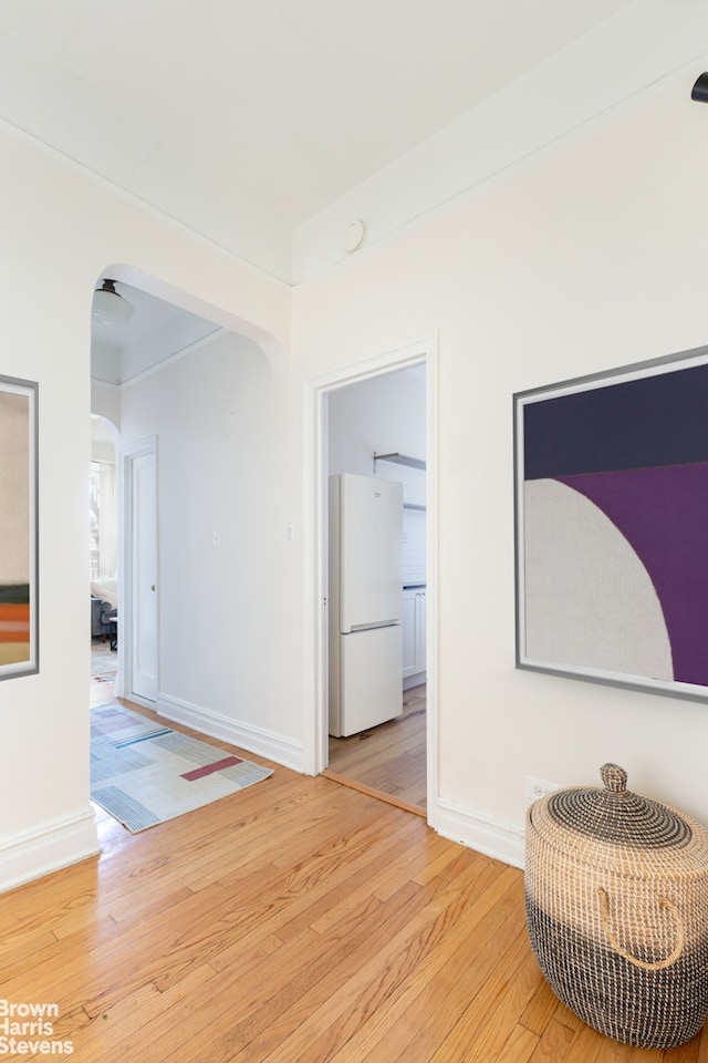 interior space with arched walkways, light wood finished floors, and baseboards