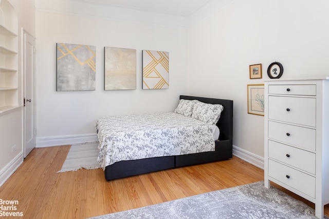 bedroom with ornamental molding, baseboards, and wood finished floors