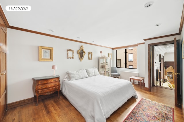 bedroom featuring visible vents, crown molding, baseboards, and wood finished floors