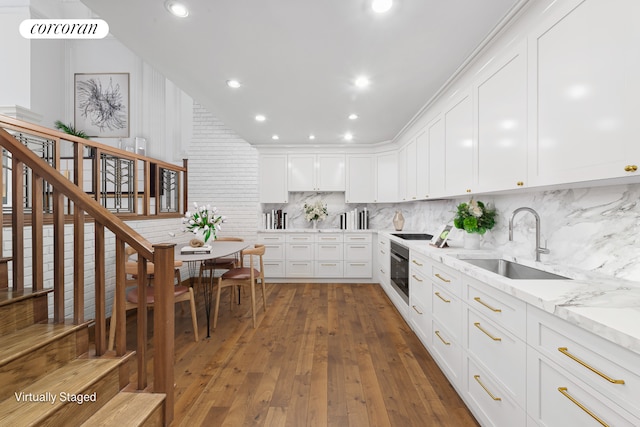 kitchen featuring dark wood finished floors, tasteful backsplash, white cabinetry, a sink, and oven