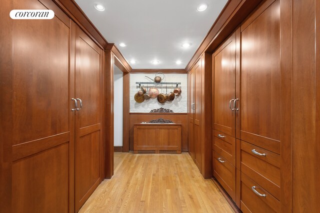 corridor with light wood-type flooring, crown molding, and recessed lighting