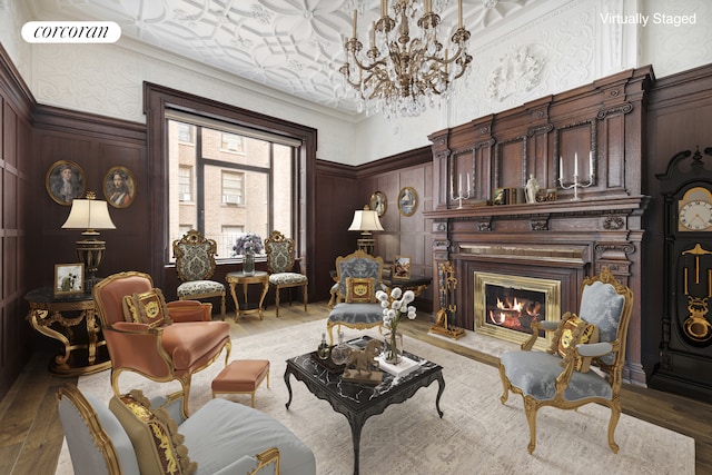 sitting room featuring visible vents, wood finished floors, crown molding, a decorative wall, and a high end fireplace