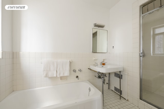 bathroom with a garden tub, tile walls, wainscoting, a shower stall, and radiator