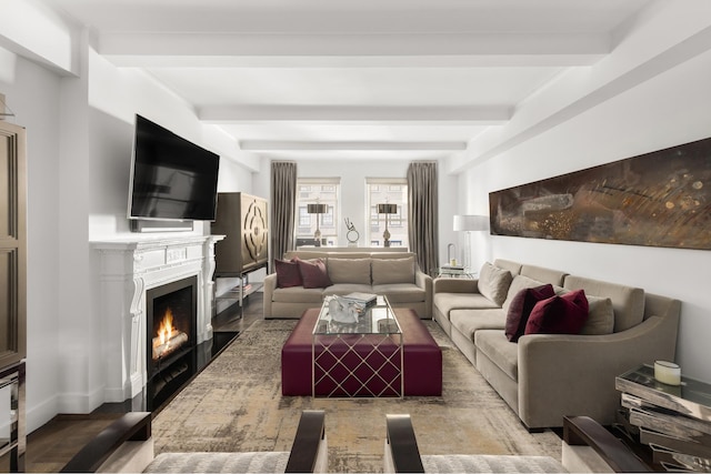 living room with a warm lit fireplace, beam ceiling, and baseboards