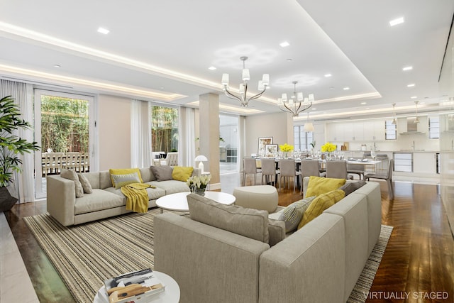 living area with a tray ceiling, a chandelier, dark wood-style flooring, and recessed lighting