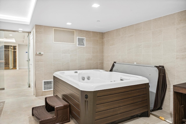 bathroom featuring visible vents, a whirlpool tub, tile walls, and tile patterned floors