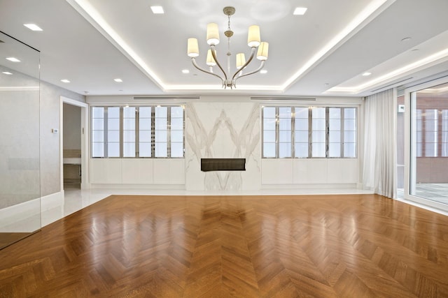 empty room featuring a tray ceiling, recessed lighting, and an inviting chandelier