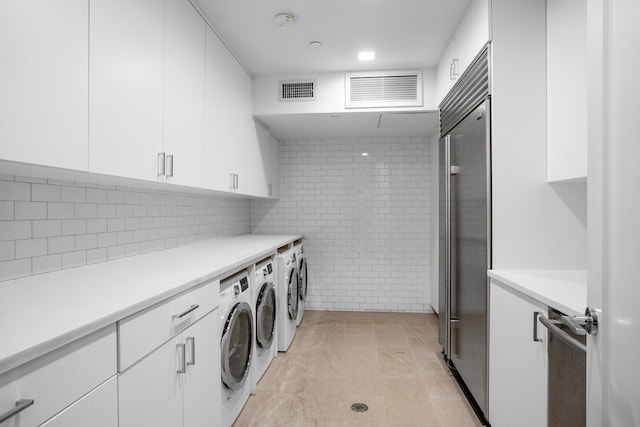 washroom with visible vents, light tile patterned floors, washing machine and dryer, and cabinet space