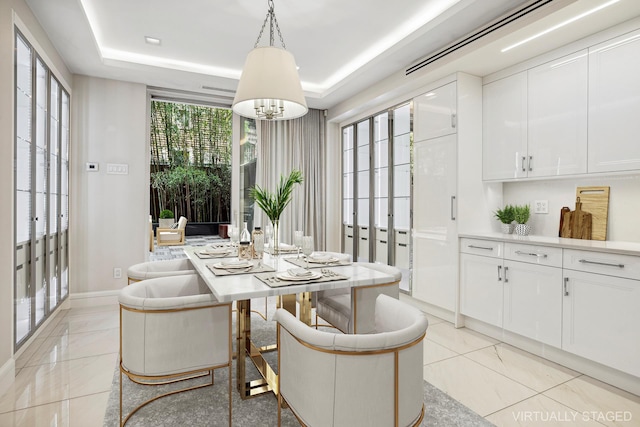 dining space featuring a chandelier, a tray ceiling, and baseboards