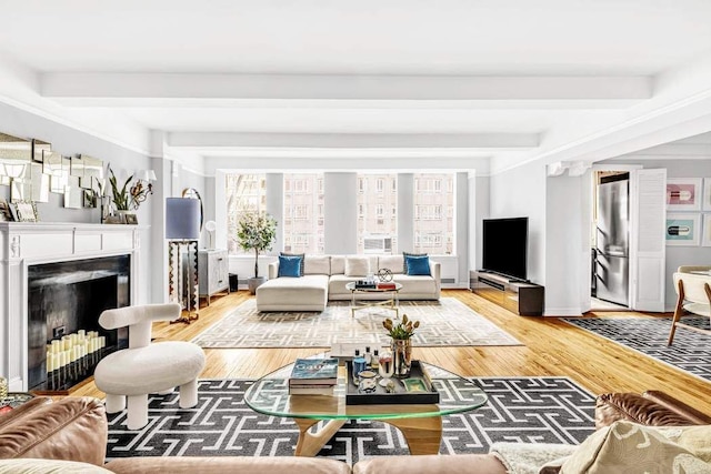 living area with light wood finished floors, beamed ceiling, a fireplace with flush hearth, and baseboards