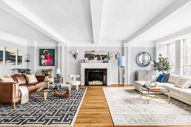 living room with beam ceiling, a fireplace, and wood finished floors