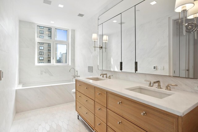 bathroom featuring visible vents, a tub with marble appearance, tile walls, and a sink