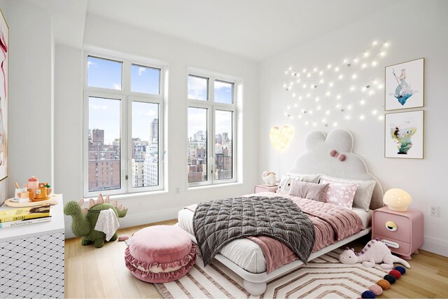 bedroom featuring a city view, baseboards, and wood finished floors