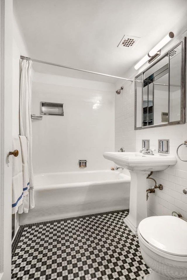 full bath with toilet, shower / tub combo, visible vents, and tile walls