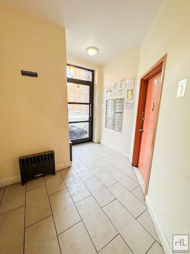 hall with mail area, light tile patterned floors, and baseboards