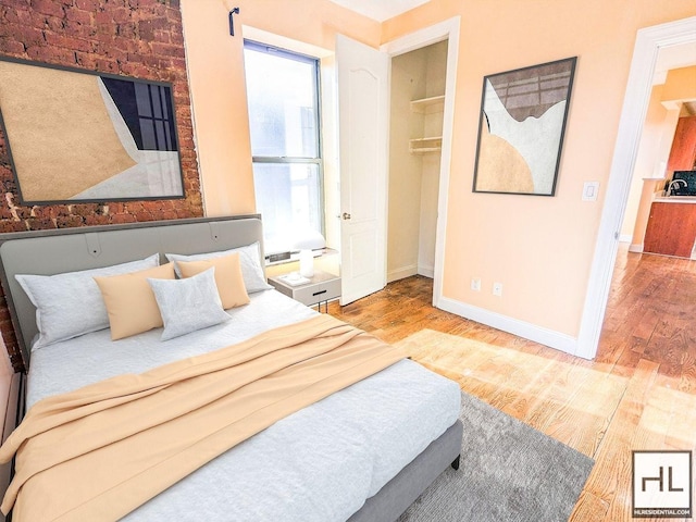 bedroom featuring a walk in closet, baseboards, and wood finished floors