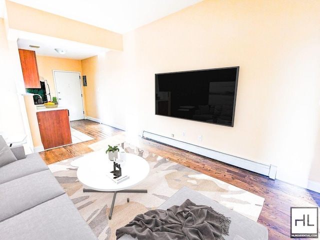 living area featuring a baseboard heating unit and light wood finished floors