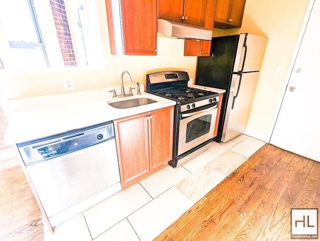 kitchen featuring stainless steel range with gas cooktop, under cabinet range hood, dishwasher, light countertops, and a sink