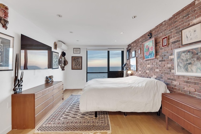 bedroom featuring recessed lighting, wood finished floors, baseboards, and brick wall