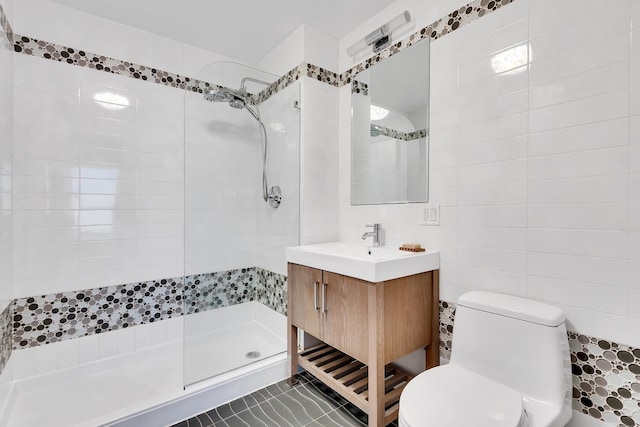 bathroom with vanity, tile walls, toilet, and tiled shower