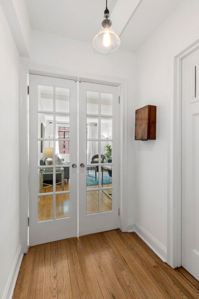 bedroom with brick wall, beamed ceiling, light wood-type flooring, and baseboards