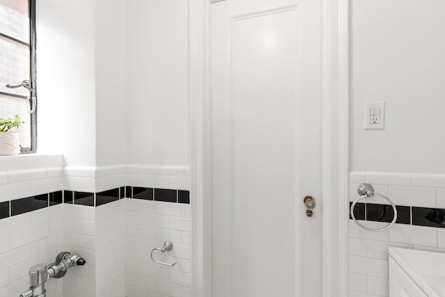 full bath featuring a wainscoted wall and tile walls