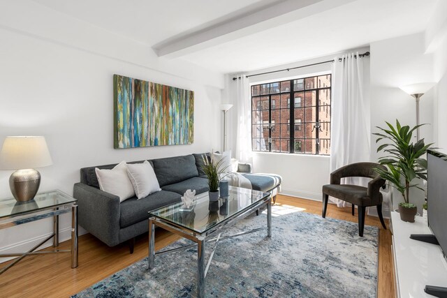 living area with wood finished floors, beamed ceiling, and baseboards
