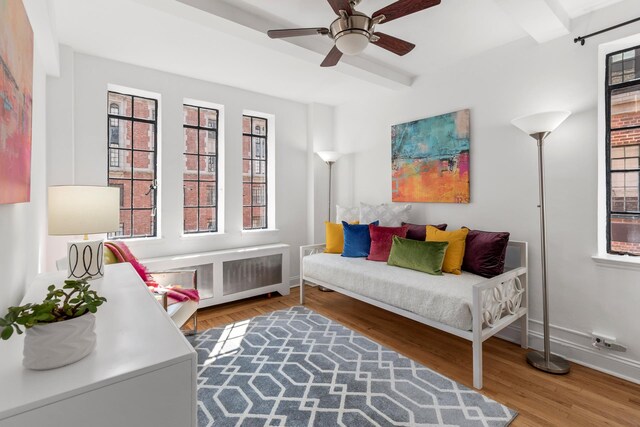 living area featuring wood finished floors, ceiling fan, beamed ceiling, and baseboards