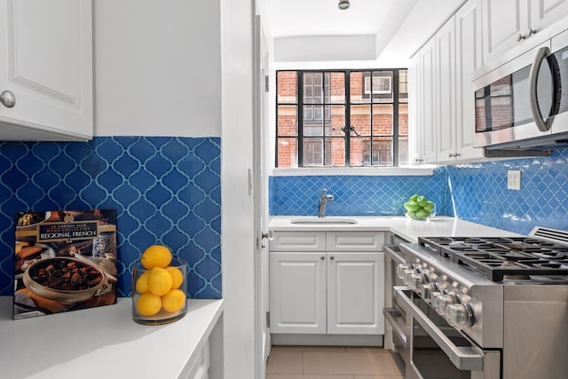 kitchen featuring appliances with stainless steel finishes, light countertops, a sink, and light tile patterned flooring