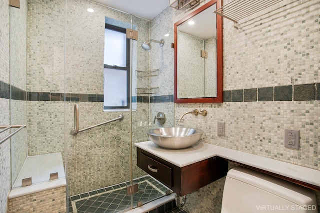 bathroom with tile walls, a shower stall, and vanity