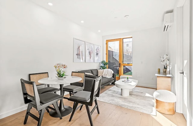 dining room featuring light wood-type flooring, baseboards, and a wall mounted AC