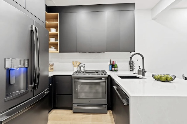 kitchen with light countertops, appliances with stainless steel finishes, light wood-style floors, a sink, and modern cabinets