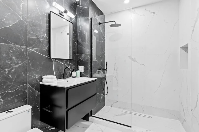bathroom featuring tile walls, toilet, vanity, a marble finish shower, and marble finish floors