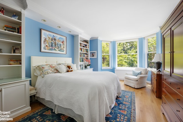 bedroom with light wood finished floors and crown molding