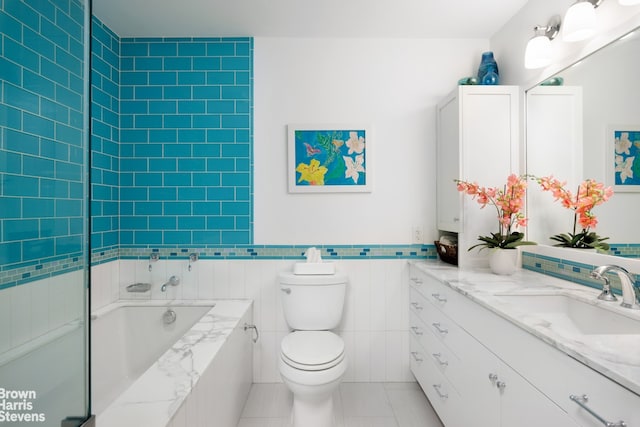 bathroom featuring tile walls, toilet, vanity, a bath, and tile patterned floors