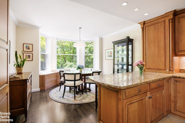 kitchen featuring a peninsula, ornamental molding, brown cabinetry, and light stone counters