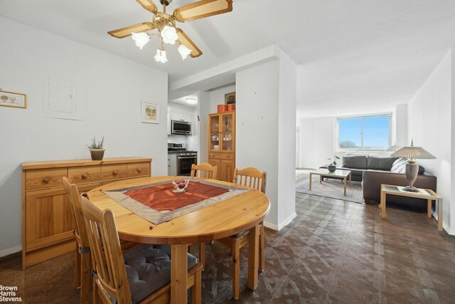 dining space with ceiling fan, dark floors, and baseboards