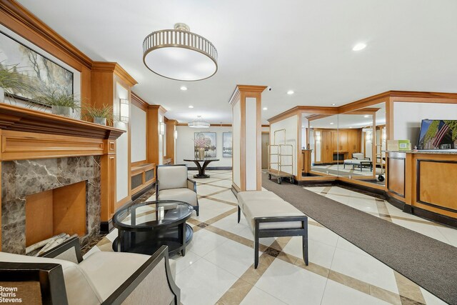 living area with recessed lighting, crown molding, a high end fireplace, and decorative columns