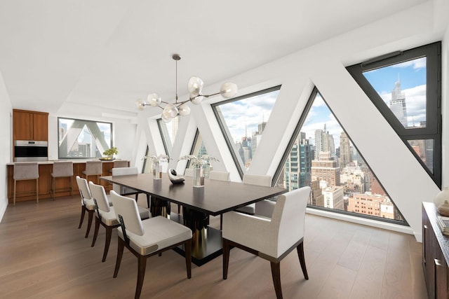 dining space with light wood finished floors, a view of city, and an inviting chandelier