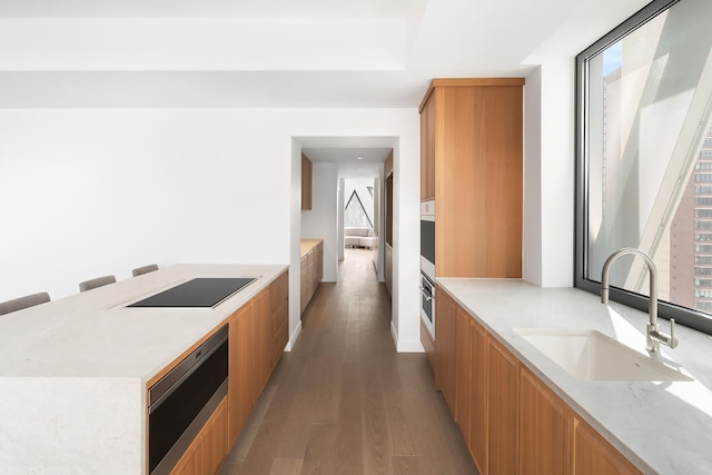 kitchen with white oven, black electric stovetop, a sink, modern cabinets, and light wood-type flooring