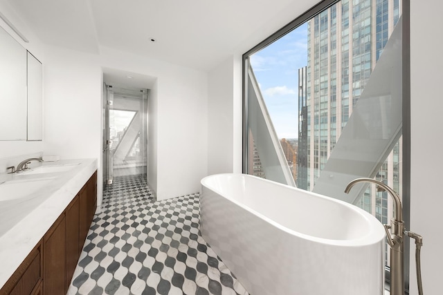 full bathroom with a sink, a soaking tub, tile patterned floors, expansive windows, and double vanity