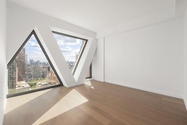 spare room featuring a view of city, baseboards, and wood finished floors