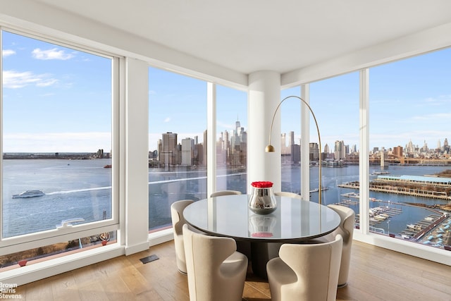 sunroom / solarium with a healthy amount of sunlight, a water view, visible vents, and a city view